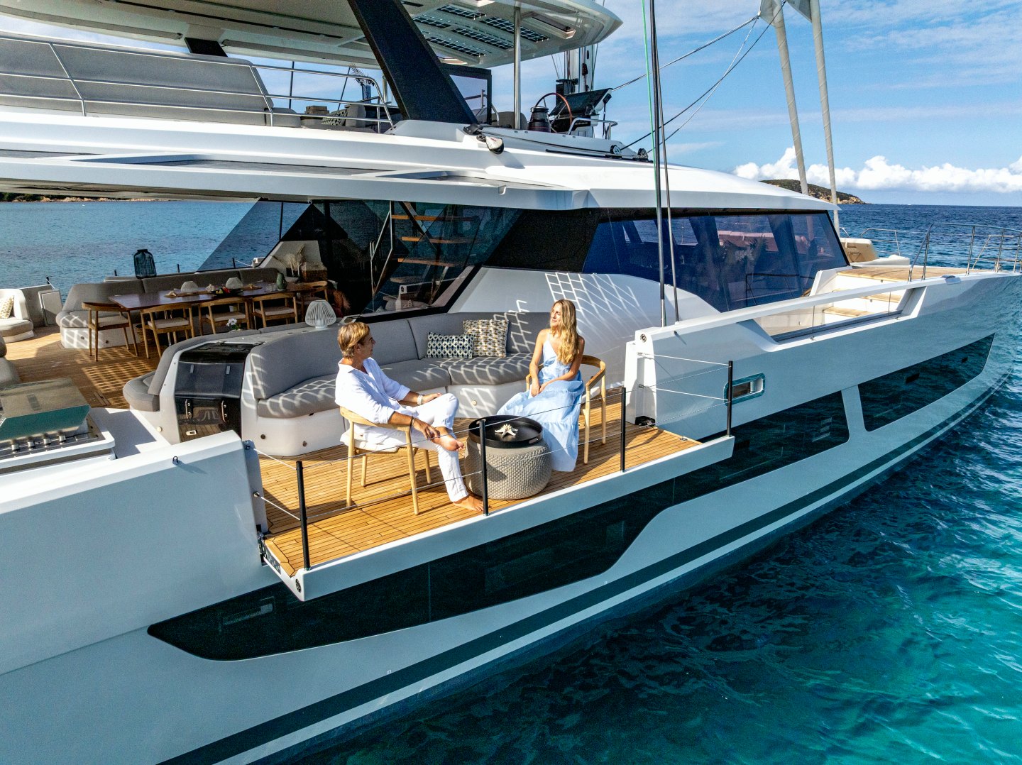 Couple relaxing on WINDKIND’s fold-down wing above turquoise water