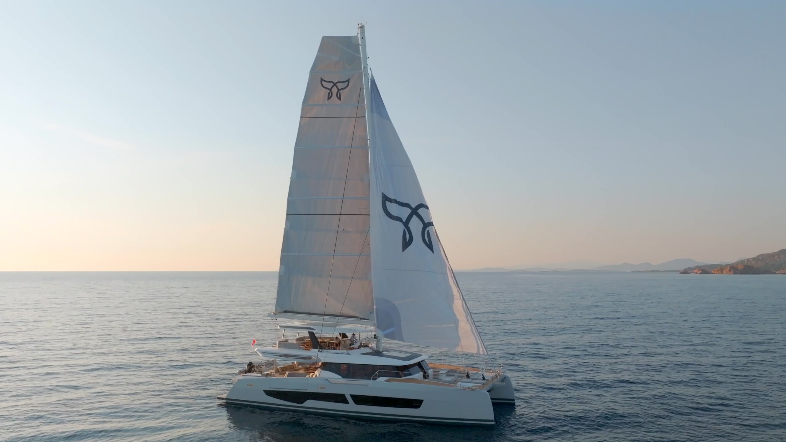 WINDKIND under sail with both logo sails in the evening light
