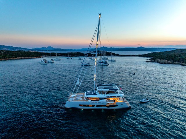 WINDKIND at anchor at dusk, lights on