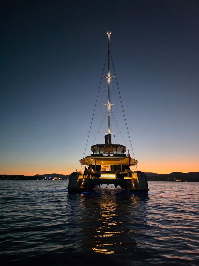 WINDKIND at anchor at dusk with her stern lights on